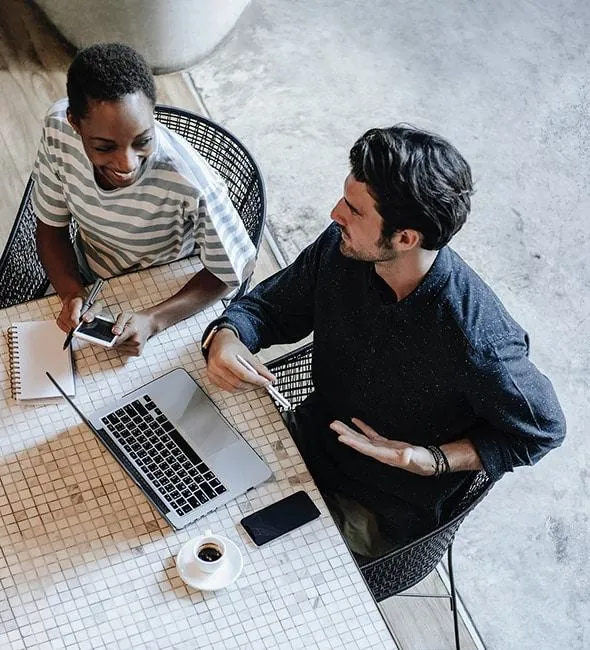 Two colleagues working together on a laptop, seen from above
