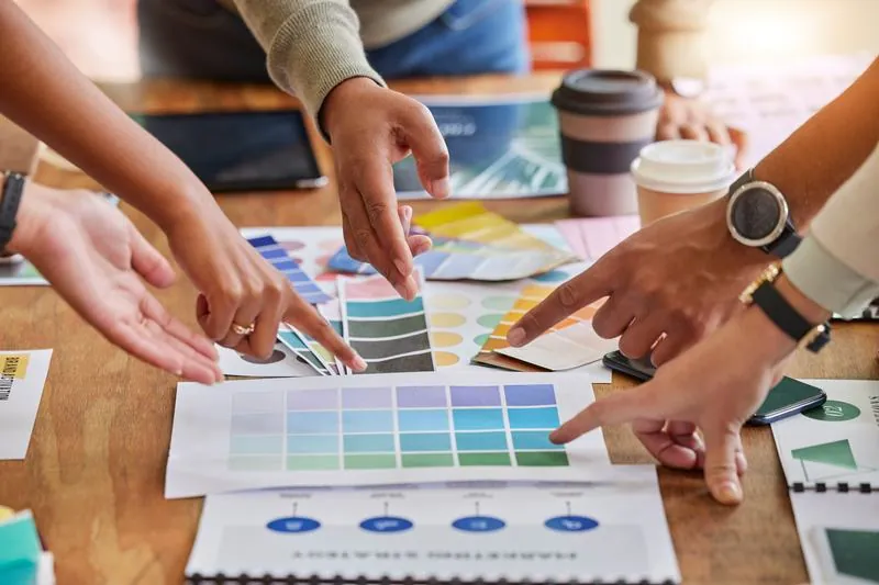 Hands pointing at colour swatches on a table: your organisation's visual identity